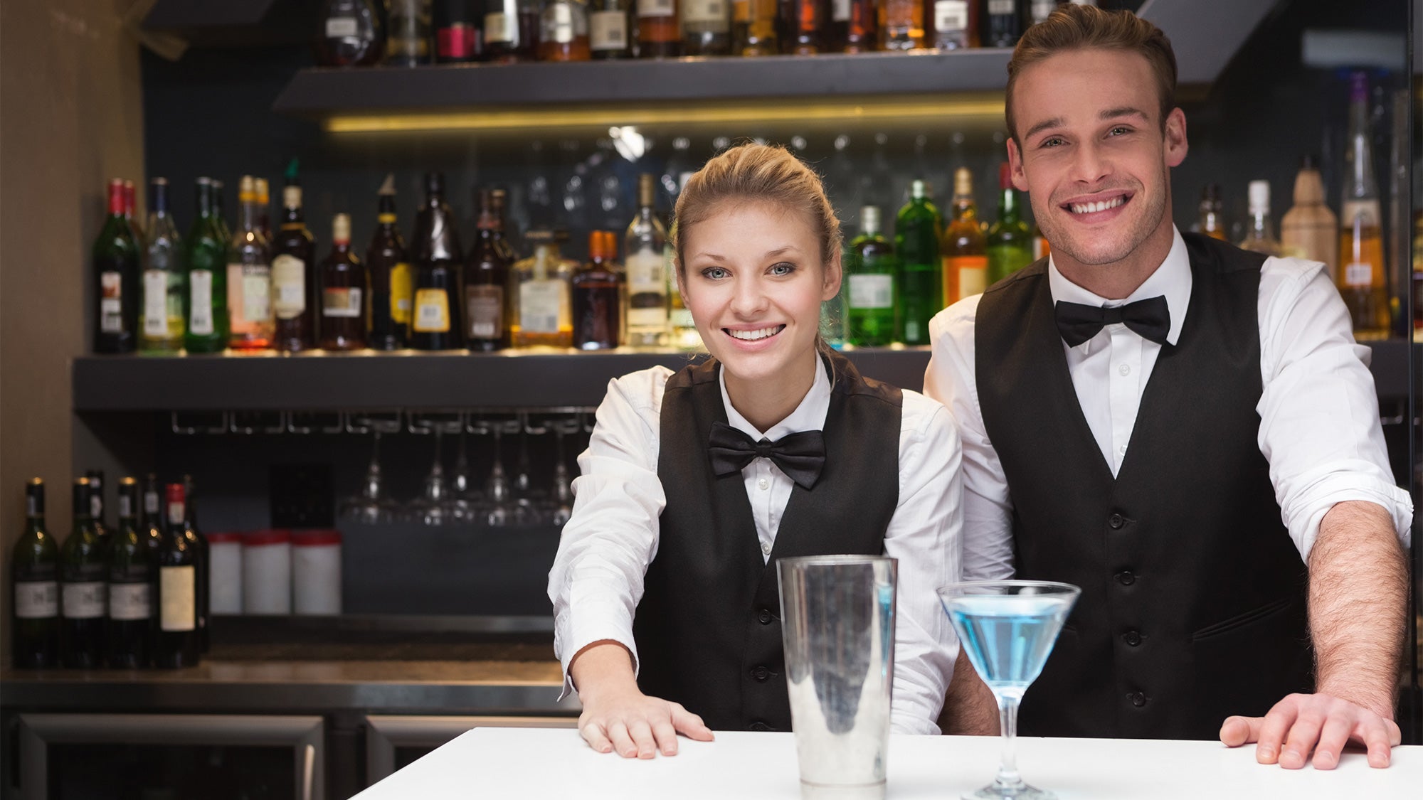 Man and woman bartenders smiling in bow ties
