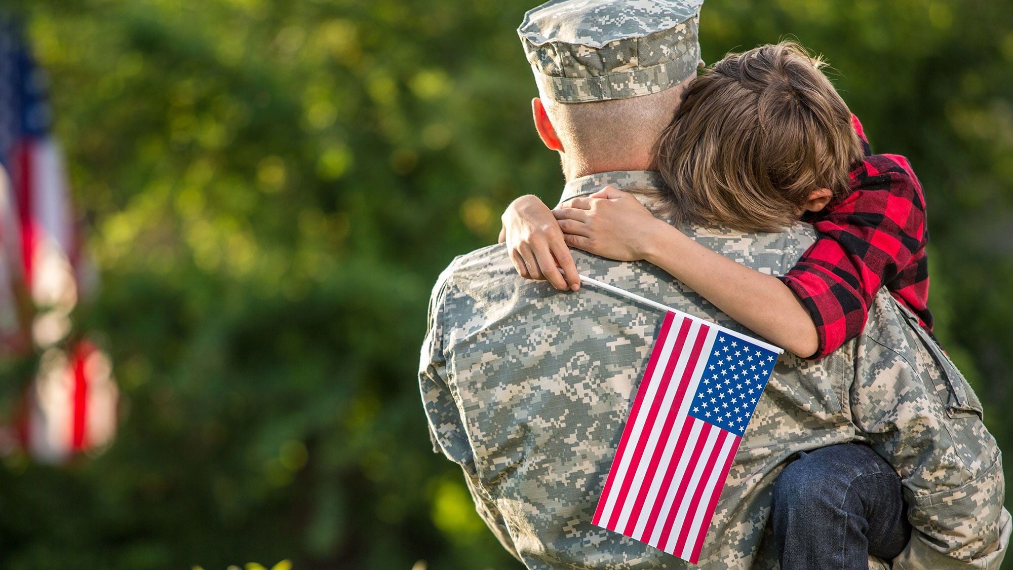 Military dad carrying his flag-wielding little boy