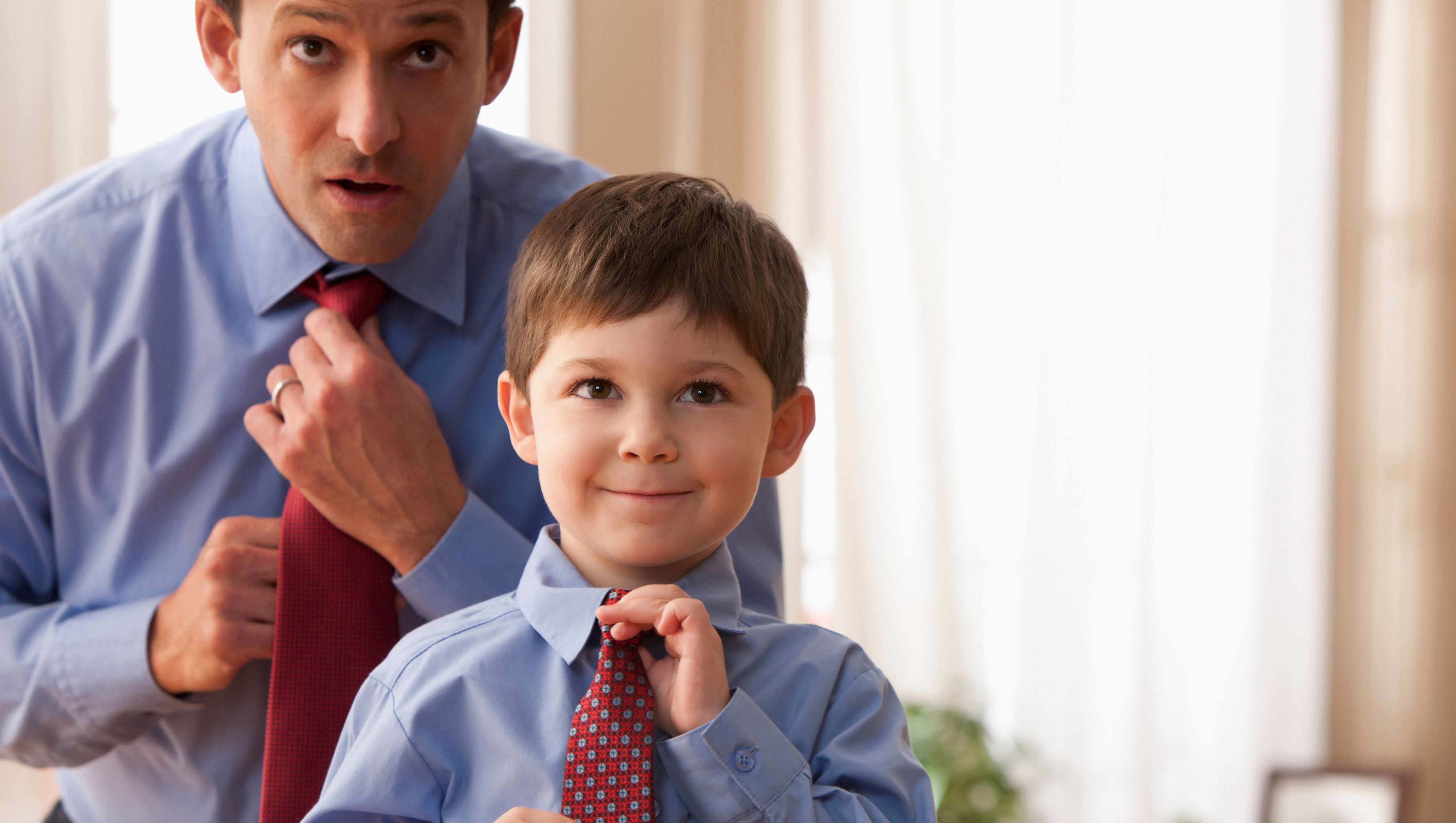 Man and his boy putting on neckties together