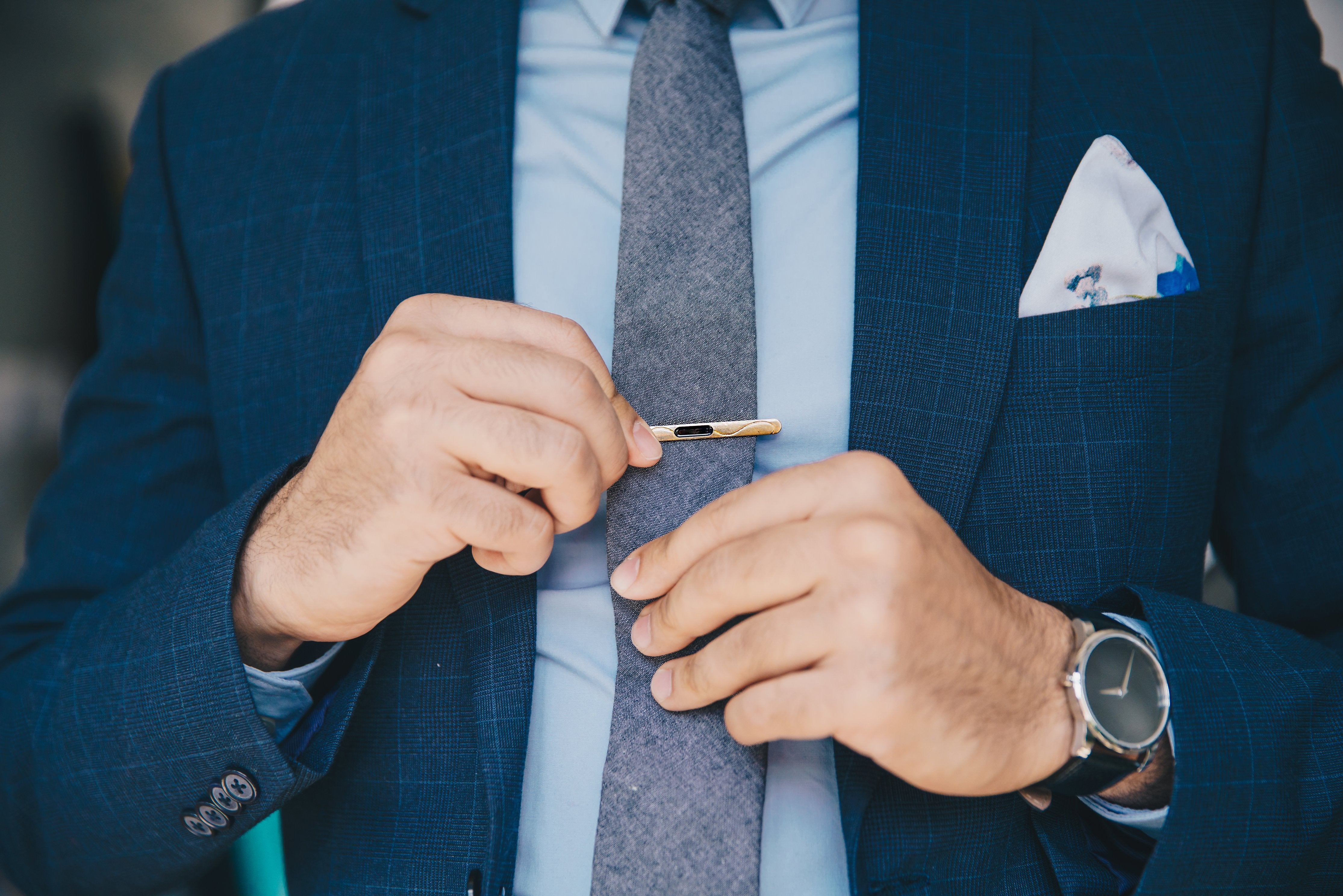 Man in suit and tie putting on a tie bar